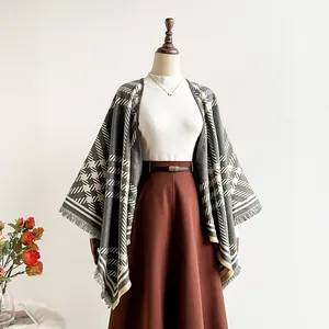 Detailed view of grey and beige houndstooth poncho with soft fringe and mixed patterns