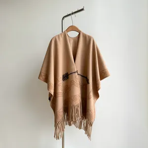 Detailed view of the camel knit poncho featuring dark brown fringe and bohemian patterns