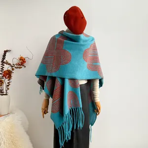 Close-up of blue tassel shawl with orange geometric patterns on a wooden mannequin