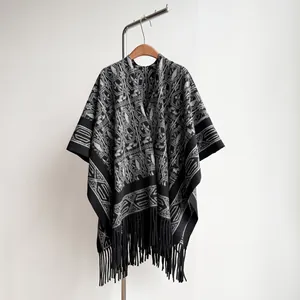 Detailed view of ethnic knit poncho featuring geometric patterns and black tassel fringe