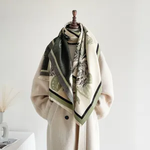 Detail des eleganten Retro-Blumen-Jacquard-Schals mit Fransen an einem beigen Wollmantel