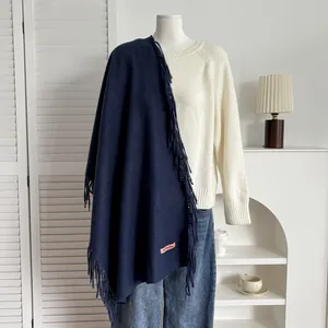 Détail d'une écharpe bleu marine aspect cachemire avec franges et étiquette sur mannequin