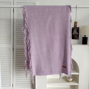 Gros plan d'une écharpe lilas au toucher cachemire avec franges et étiquette tissée