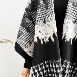 Detailed macro view of the houndstooth pattern on a thick monochrome knit poncho