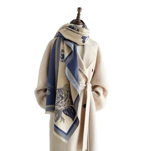 Eleganter Kaschmir-Schal mit Blumenmuster und Fransen auf beigem Wollmantel