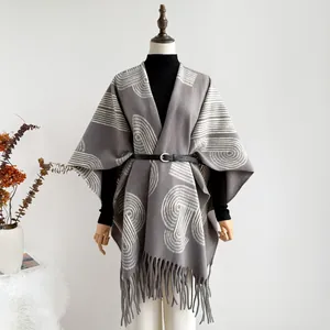 Detail of grey knitted shawl with white geometric spiral patterns and fringe trim