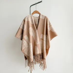 Detail of camel ethnic shawl featuring white geometric patterns and long fringe tassels