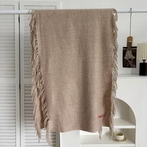 Détail de l'écharpe en imitation cachemire camel avec franges et écusson brodé