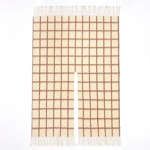 Detail des beigebraun karierten Strickponchos mit Fransen und dem mittigen Schlitz-Ausschnitt