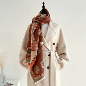 Détail du châle en cachemire à motif camélia avec franges sur un manteau beige chic