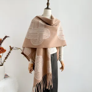 Detail of camel knit shawl featuring white geometric patterns and soft tassel edges