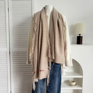 Détail d'une écharpe imitation cachemire camel clair avec franges et étiquette tissée