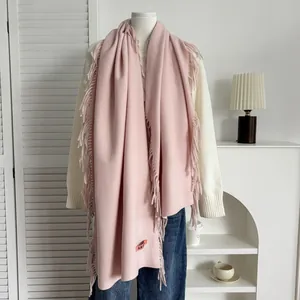 Détail d'une écharpe rose en cachemire synthétique avec franges et étiquette tissée