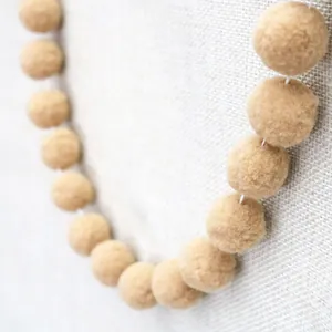 Close-up of beige wool felt balls on white string for DIY party decorations