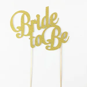 Close-up of glitter gold Bride to Be cake topper with double wooden sticks for weddings