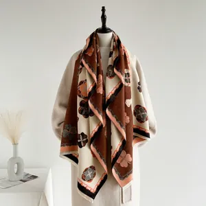 Détail d'écharpe à motif camélia avec franges drapée sur un manteau d'hiver beige