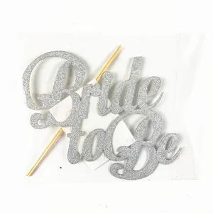 Detail of silver glitter Bride to Be cake topper with sticks in retail packaging