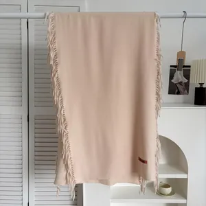 Détail de l'écharpe rose pâle en imitation cachemire avec franges et étiquette de marque