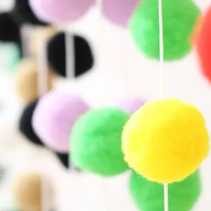 Macro shot of colorful soft pom poms on string for children's birthday party decoration