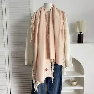 Détail d'une écharpe douce rose pâle type cachemire avec franges et petite étiquette