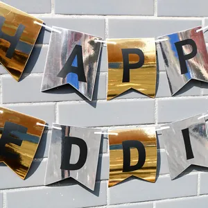 Golden and silver Happy Birthday banner flags hanging on a grey brick wall background