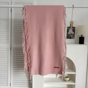 Écharpe rose effet cachemire avec franges et étiquette de marque sur un cintre