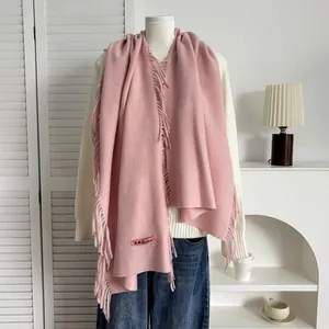Gros plan sur une écharpe rose style cachemire avec franges et étiquette tissée design
