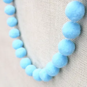 Macro detail of sky blue fuzzy pom pom garland string for DIY party decoration