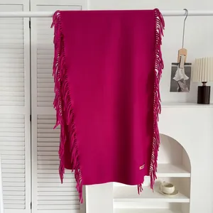 Détail d'une écharpe douce rouge rose toucher cachemire avec texture fine et longs franges