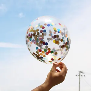 Close-up of 12-inch transparent balloon with multi-colored confetti inside against blue sky