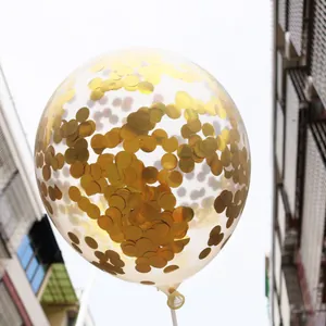 Detail of transparent balloon filled with shiny gold round confetti and white support rod