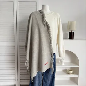 Détail d'une écharpe gris clair aspect cachemire avec de longues franges et étiquette