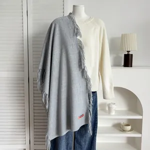 Détail d'une écharpe grise en cachemire avec franges et étiquette sur un mannequin
