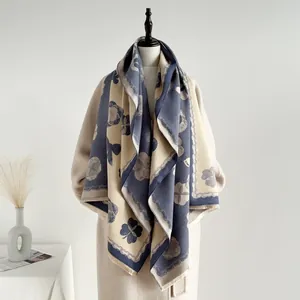 Détail des franges douces et du motif floral bleu marine sur le châle d'hiver