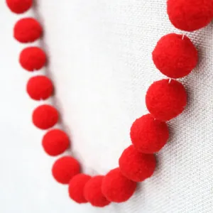 Close-up of fluffy red pom poms string for DIY kids birthday party and holiday decor