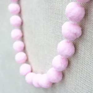 Close-up of soft pink pom poms on a string for DIY kids birthday party decoration