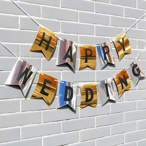 Golden and silver HAPPY WEDDING swallowtail banner hanging on a gray brick wall background