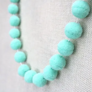 Detail of soft mint green plush balls on white string for DIY birthday party decor