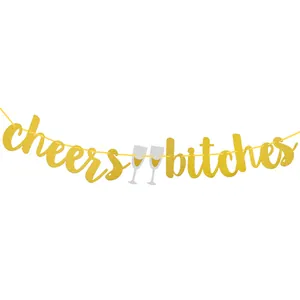 Close-up of golden glitter 'cheers bitches' banner with silver champagne glasses detail