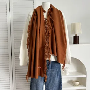 Détail d'une écharpe marron en cachemire avec de longues franges et étiquette rose