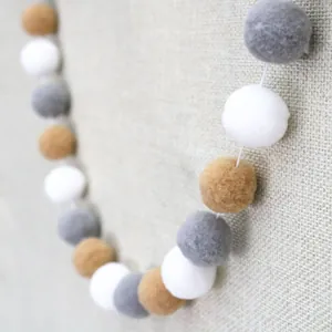 Detailed macro view of soft white, gray and mustard yellow wool felt ball garland