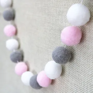 Detail of soft white pink and grey plush balls on a rustic linen background