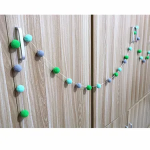 Close-up of multicolored felt pom pom garland hanging on a wooden cabinet handle