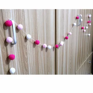 Close-up of soft red pink and white pompoms on a string for festive party decoration