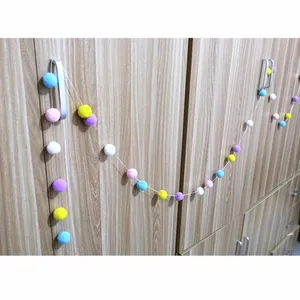 Colorful plush ball garland hanging on a wooden cabinet handle for party decoration