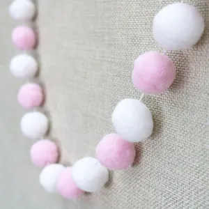 Pink and white fuzzy pom-pom garland for children birthday party or nursery decoration