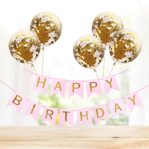 Pink Happy Birthday banner paired with five gold confetti balloons on a wooden table