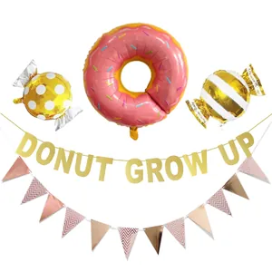 Close-up of pink donut balloon and gold glitter Donut Grow Up party banner set