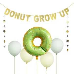 Close-up of glittery Donut Grow Up banner and donut balloon for birthday party decorations