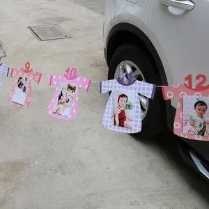 Detail of 1st birthday banner with baby photos and pink numeric clothing-shaped cards